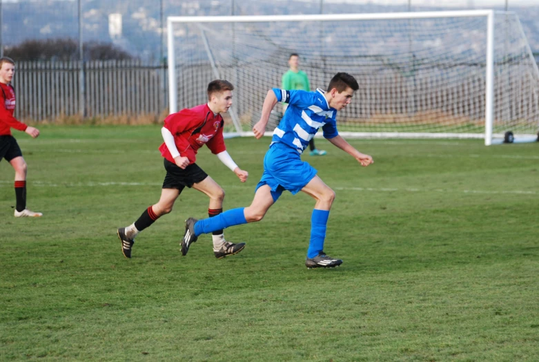 soccer players in blue and red running toward the ball