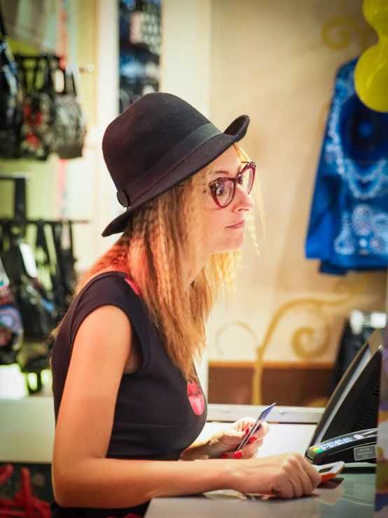 a woman in a hat sitting in front of a laptop