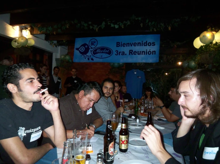 several people are sitting at a dinner table with beer and water