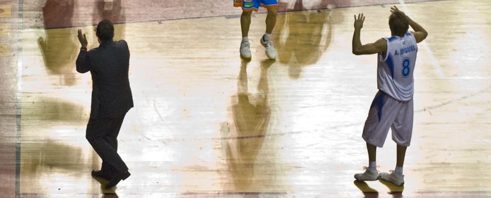 a man is trying to dunk at a game with three players