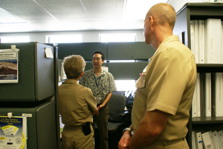 three people in uniforms looking at an employee working