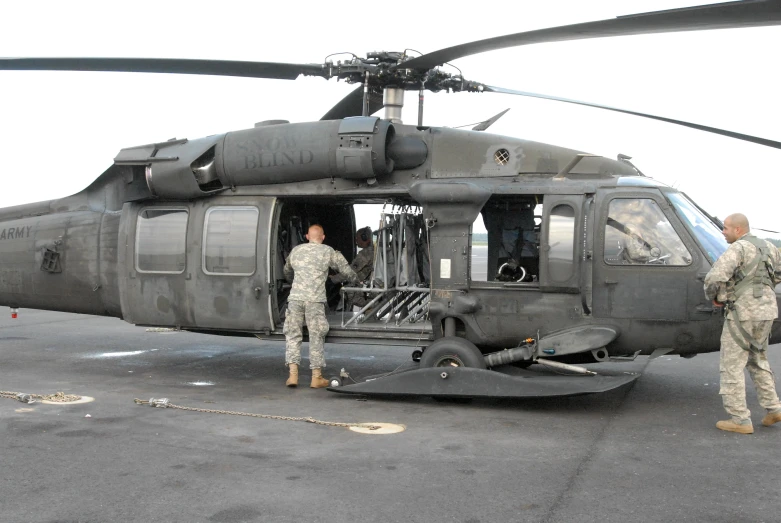 two soldiers standing in front of a helicopter on the tarmac