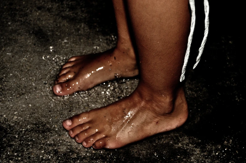 a woman standing with her wet feet on top of a concrete ground