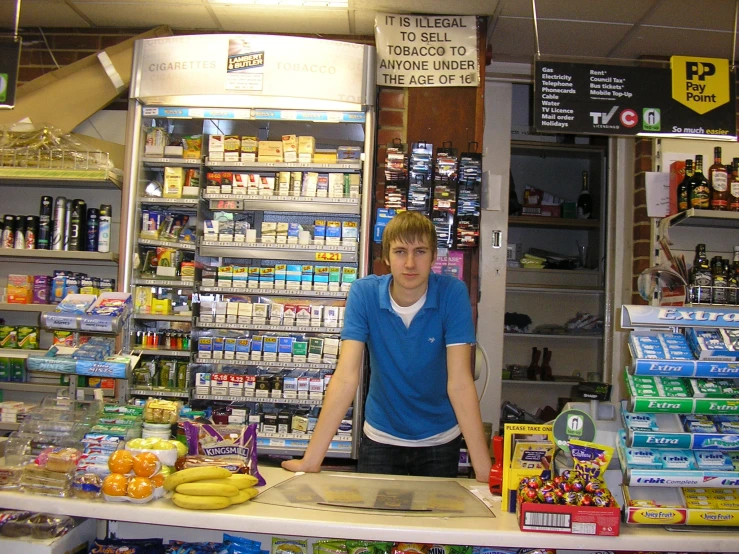 man standing behind counter in store with goods for sale