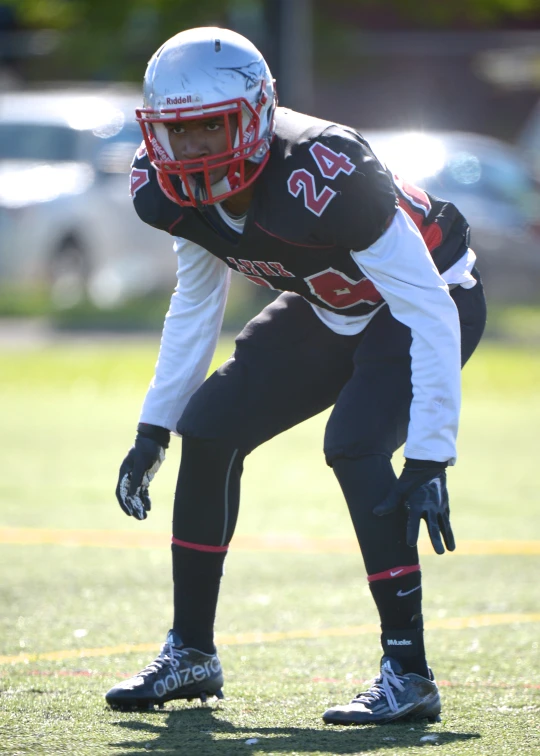 a man bent down holding onto his knee while wearing a football uniform