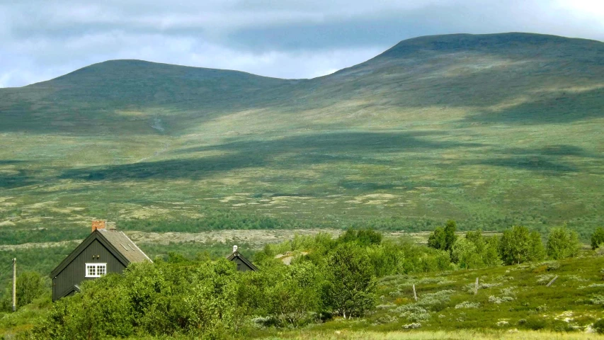 a very small house in a field near mountains