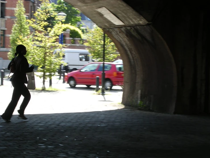 the girl is walking through a tunnel under cars