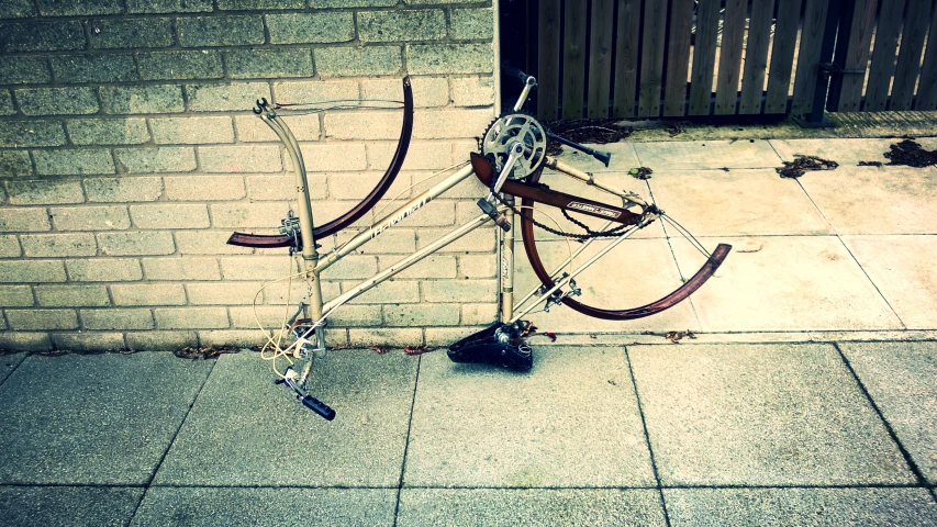 a broken bicycle locked to the side of a building