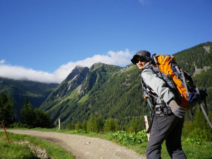 man standing on dirt road in valley with mountain in background