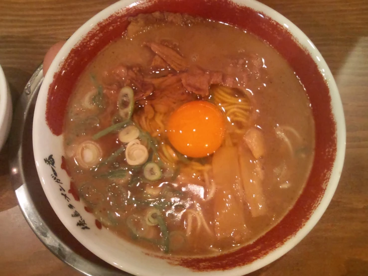 an asian soup with beef, noodles and an egg in it