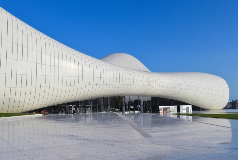 the large, curved building is white and has many windows