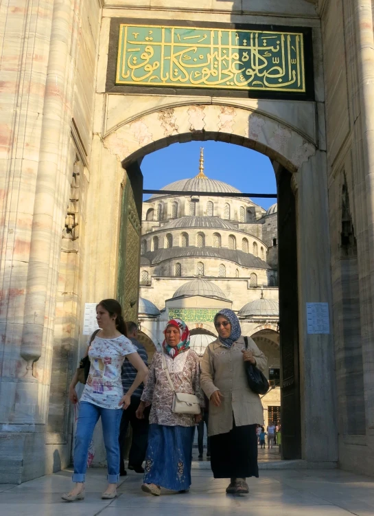 people stand under the islamic structure at the entrance to the palace