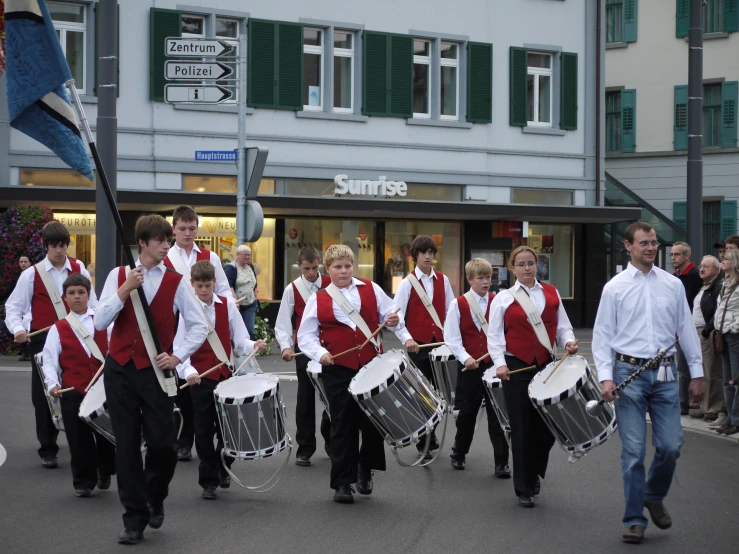 some people are marching down a street and holding drums