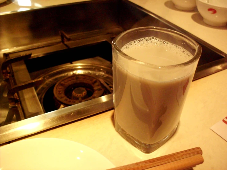 there is a drink that is in the glass next to a gas stove