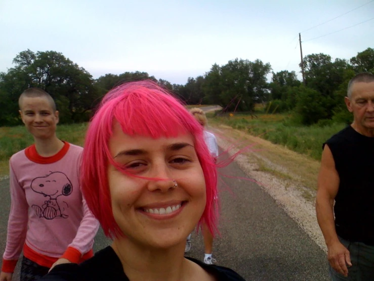 a girl with pink hair and piercing is smiling at the camera