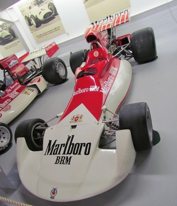 two racing cars sit on display in a museum