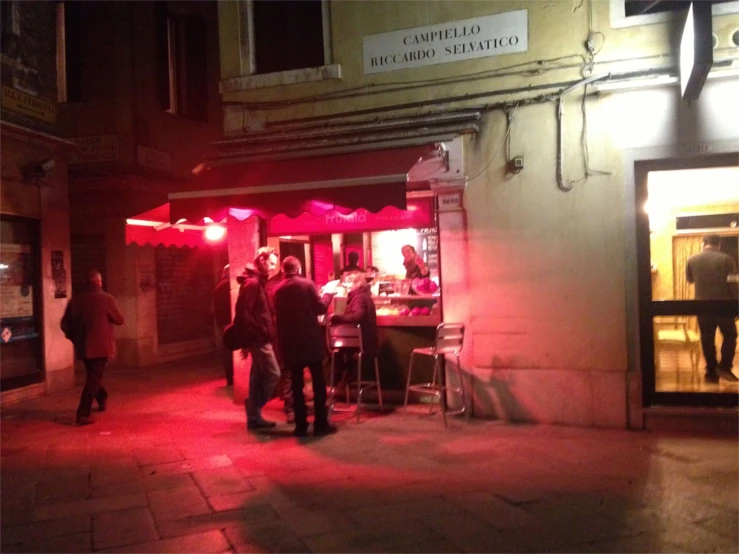 people standing on the sidewalk outside of an establishment at night