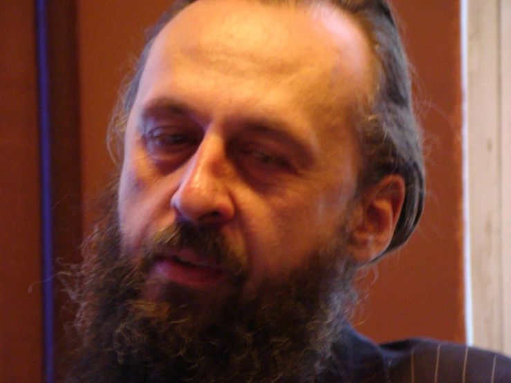 a man with long gray hair and beard, wearing a suit