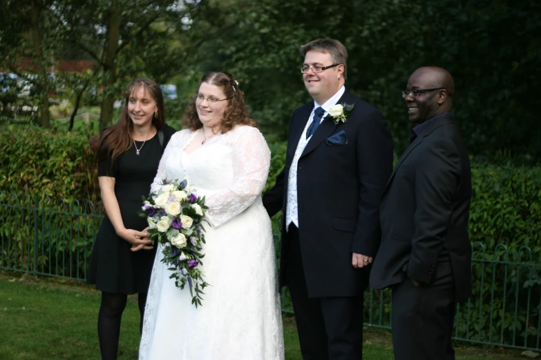 two men and two women standing next to each other on grass