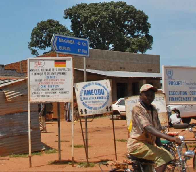 a man riding a bike next to a tall blue and white street sign