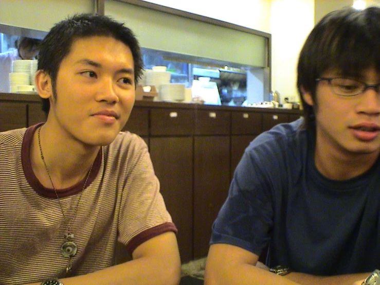 two men sitting at a table with cell phones on their hands