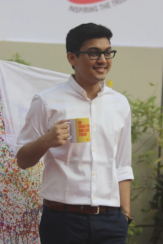 a man holding a mug while standing up with a curtain