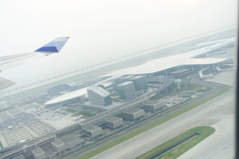 an airplane wing over an airport and surrounding buildings