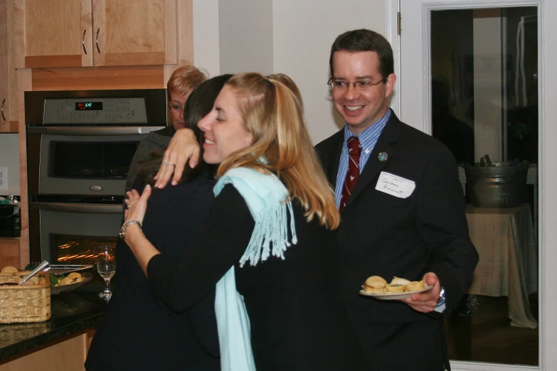 a group of people standing in a kitchen next to each other