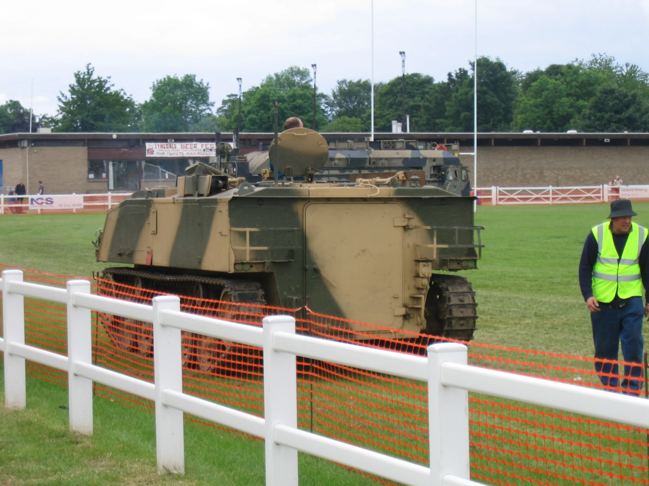 a man standing by an army tank in the middle of a field