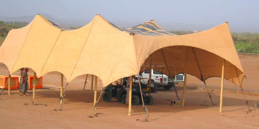 two big tents under some poles on the beach