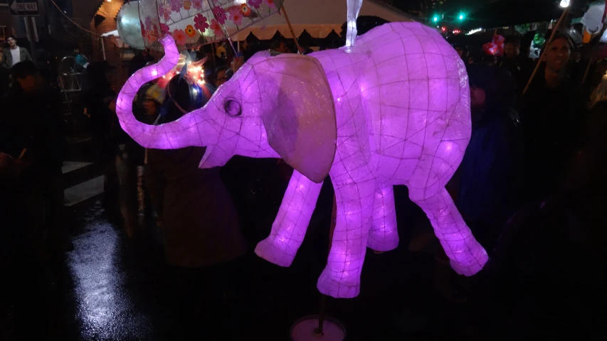 a large purple elephant in the middle of a crowd