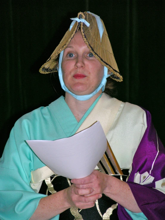 a woman dressed in costume and holding a large paper in her hands