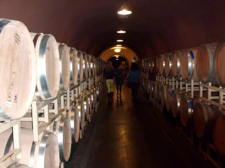 several barrels stacked high and behind them are people walking