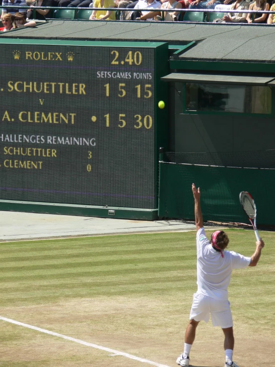 a tennis player is serving the ball in front of a score board