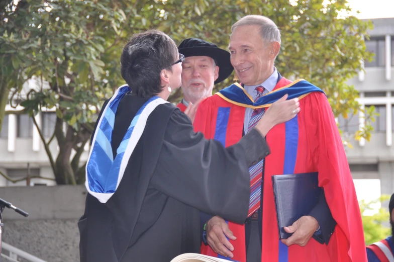 a graduate being congratulated by another gentleman and his other fellow