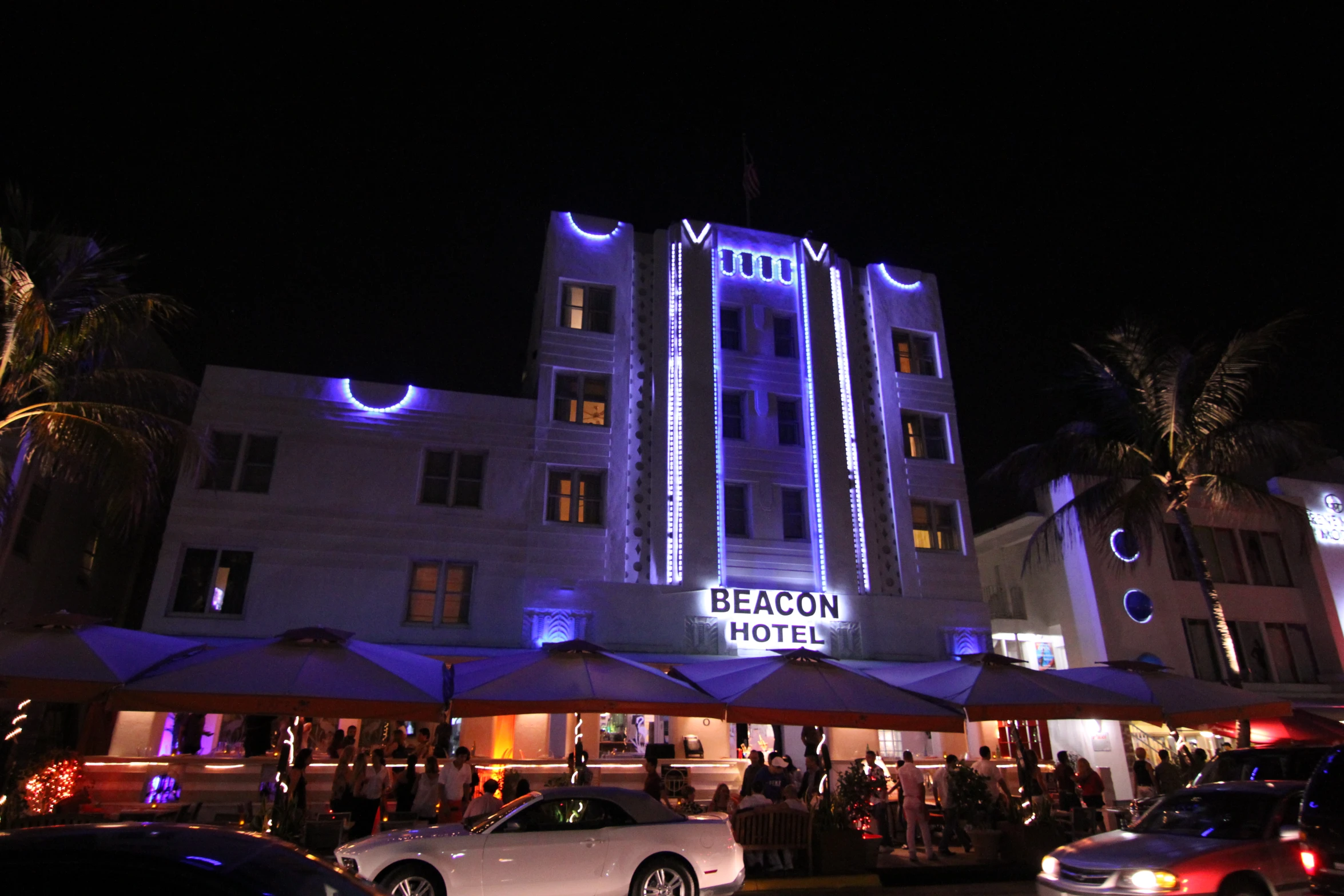 the beach front building has blue light and umbrellas