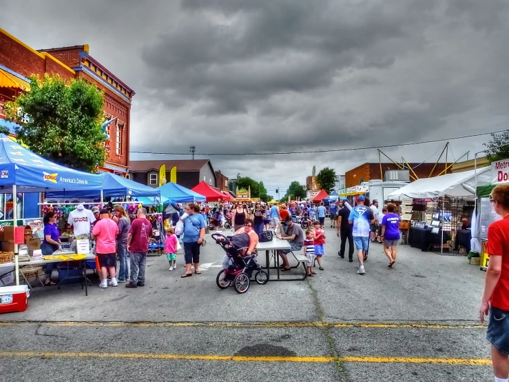 people walking around in an outdoor market under storm clouds