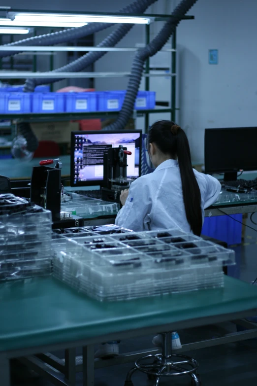 a woman working in a factory behind a desk with lots of plastic containers