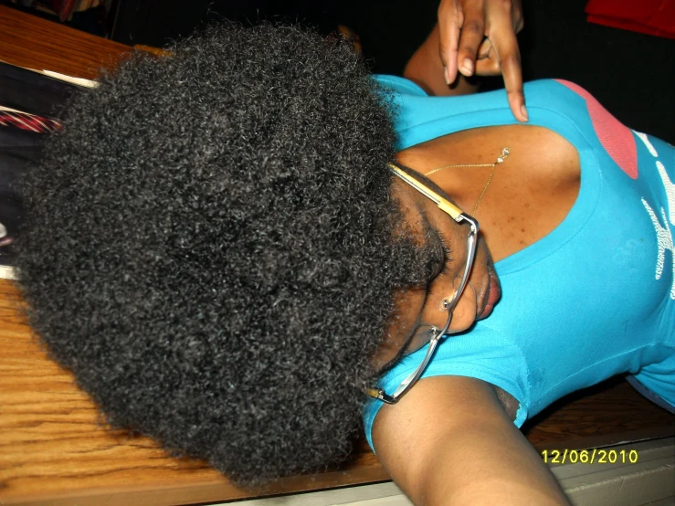 a woman with large afro in a blue shirt touching her finger