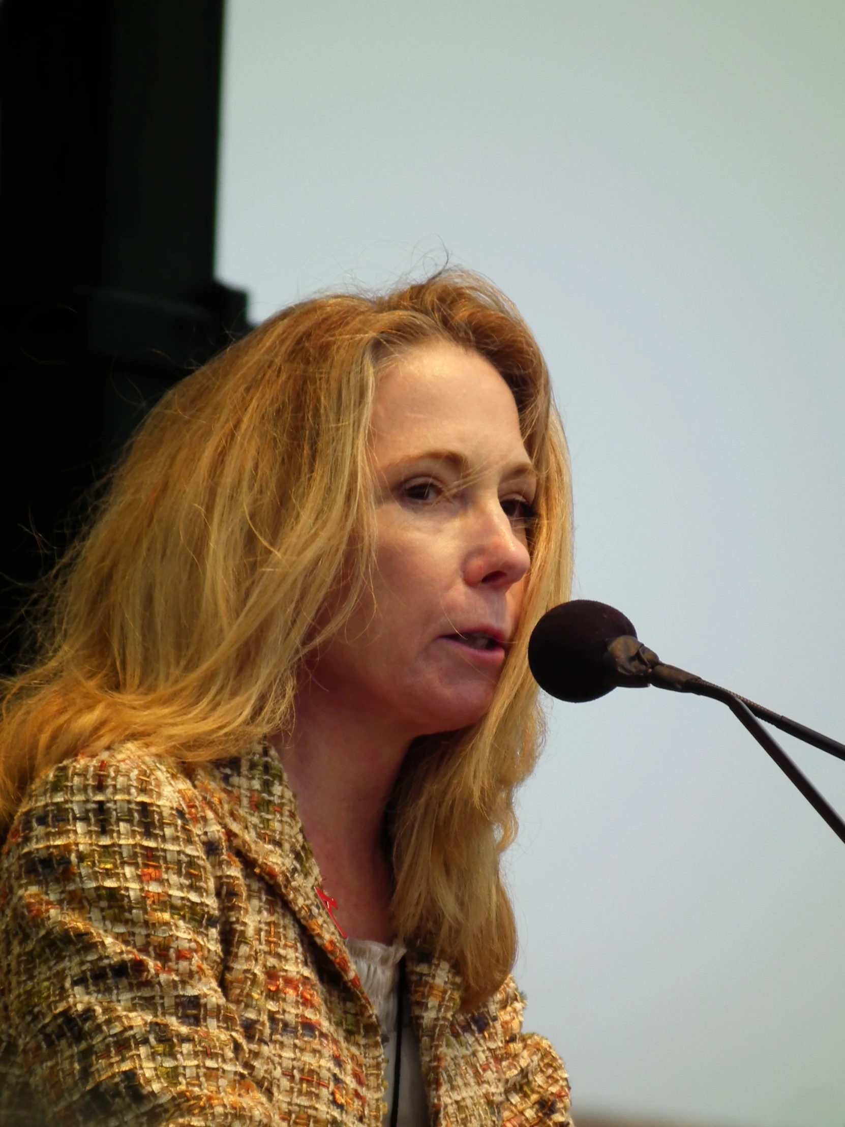 woman at microphone looking upward as she speaks into a mic