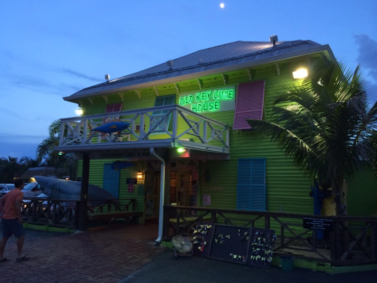 people stand outside the exterior of a building with shutters open and green paint