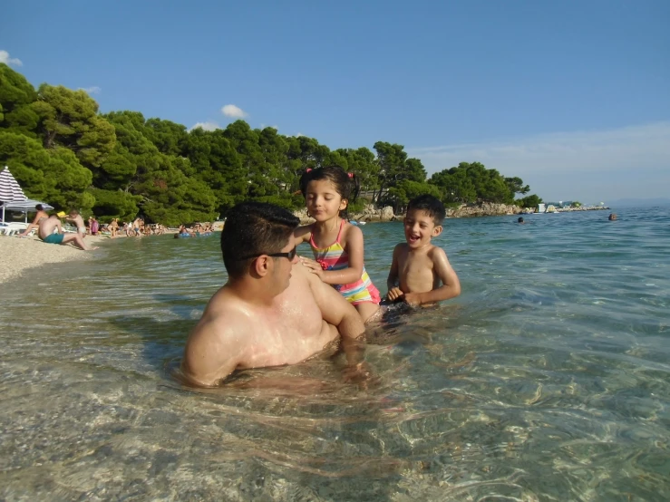 two boys and a girl in the water on the beach