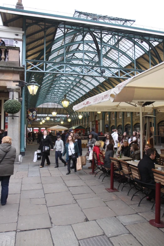 people walking down a crowded sidewalk past a restaurant