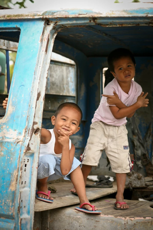 two little boys are standing on the back of a truck