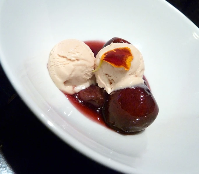 two pieces of fruit and ice cream sit in a white plate