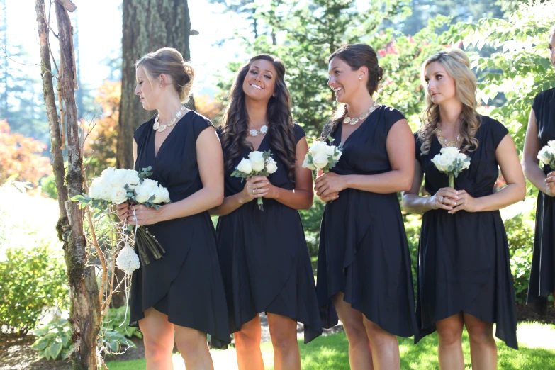 five women in black dresses, all looking at soing