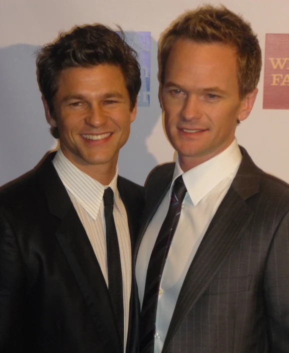 two men in suits and ties pose for the camera