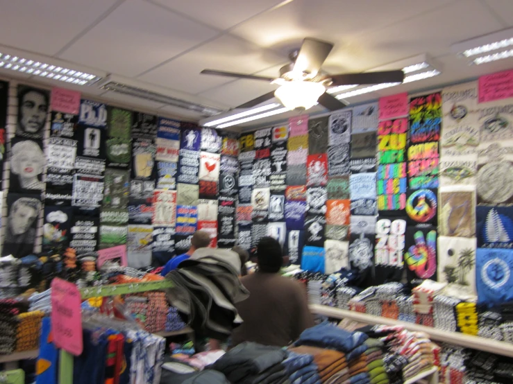 two men stand in front of a wall of shirts