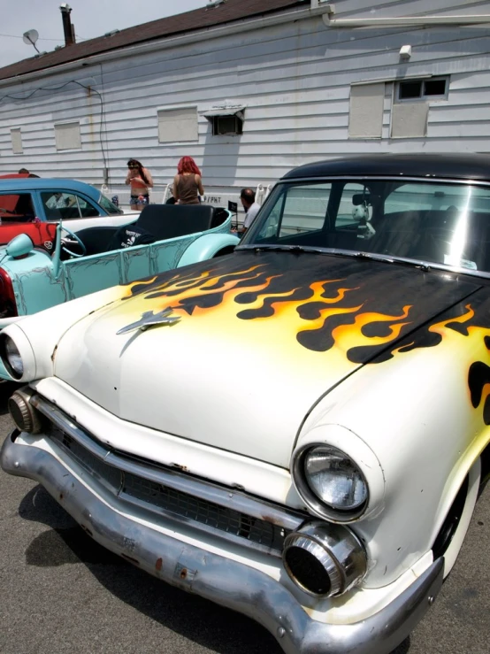 an old car painted yellow, orange and black with flames on the grills