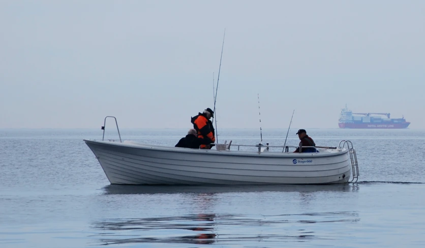 two people on a boat with fishing rods in the water